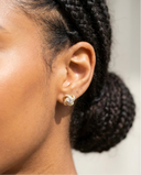 Close-up of an ear with a diamond earring, hair styled in braids.
