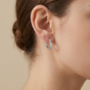 Silver hoop earrings worn by a person with a neutral background