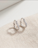 Pair of silver hoop earrings on a light beige surface