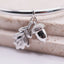 Silver bracelet with acorn and leaf charms on a wooden surface