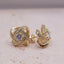 Gold earrings with interwoven design and clear gemstones on a light background