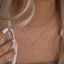 Woman wearing a gold necklace with a cross pendant.