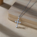 Silver cross pendant necklace on a wooden surface