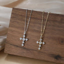 Two diamond cross necklaces on a wooden surface