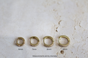Set of gold hoop earrings with measurements on a textured white surface