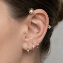 Close-up of an ear with gold earrings and a gray background
