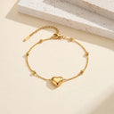 Flat lay of the Statement Heart Beaded Anklet in gold on a neutral background.