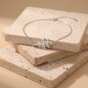 Sculpted Leaf Pendant bracelet - Sterling SilverA delicate silver chain bracelet with a detailed leaf-shaped charm, displayed on stacked beige travertine stone tiles against a warm beige background.