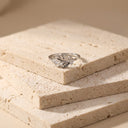 Leaf Open Band Ring – Sterling Silver. A silver ring with a textured, organic leaf-like pattern, resting on a stack of beige stone tiles.