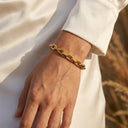 A close-up of a person's wrist wearing Elara Link Bracelet styled with a white long-sleeve top and a blurred outdoor background.