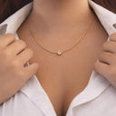 Mini CZ Necklace – Gold PVD Plated Stainless Steel. Gold necklace with a white gemstone worn by a person in a white shirt.