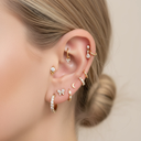 Close-up of an ear with multiple gold and diamond earrings on a neutral background