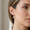 Close-up of a woman wearing a gold earring with a neutral background