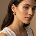 Chunky Pearl & Crystal Hoop Earrings- A close-up of a woman wearing a gold and white beaded drop earring, shown from the side against a warm beige background.