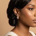 Chunky Pearl & Crystal Hoop Earrings- A close-up side profile of a woman wearing a gold huggie hoop earring with a textured, organic organic-shaped gold setting and clear stones, set against a solid beige background.