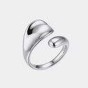 A polished silver-toned open ring with a smooth, organic, wavy design, shown on a light gray background.