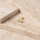 Star & Bar CZ Cartilage Stud- cartilage piercing stud with a small barbell and a clear crystal star, resting on beige travertine stone tiles.