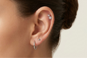 Close-up of an ear with silver earrings on a neutral background
