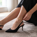 statement-heart-beaded-anklet-gold-evening-look- A close-up lifestyle shot of Model wearing the Statement Heart Beaded Anklet in gold with black heels and an elegant evening outfit.