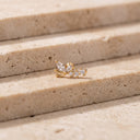 Flora Vine CZ Cartilage Stud - A delicate gold floral stud earring with clear marquise and round-cut stones, resting on beige stone steps.