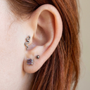 Close-up of an ear with Titanium Snake Tragus Earring on a plain background