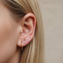Close-up of an ear wearing gold earrings with a neutral background