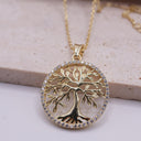 Gold tree-shaped pendant necklace on a light background