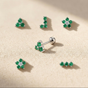 Set of emerald green gemstone earrings on a beige background