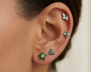 Close-up of an ear wearing green gemstone earrings with a neutral background