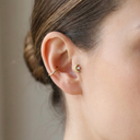 Close-up of a person wearing a gold tragus earring with a blurred background