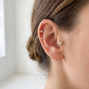Close-up of an ear wearing two stud earrings with a blurred background
