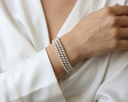 Silver beaded bracelet on a person's wrist against a white background