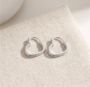 Pair of silver hoop earrings on a textured beige surface