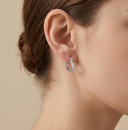 Silver hoop earring worn by a person with a neutral background