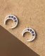 Silver crescent moon earrings with blue gemstones on a wooden background