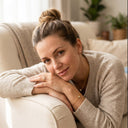 Woman in a beige sweater sitting on a couch in a cozy living room.