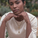 A woman wearing a cream-colored satin blouse wearing Rosario beaded cross necklace 