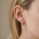 Close-up of an ear wearing a silver earring with clear stones.