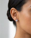 Close-up of an ear wearing a diamond stud earring against a neutral background