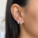 Close-up of an ear wearing two silver hoop earrings with a neutral background