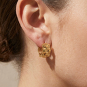 Gold hoop earring worn by a person with a neutral background